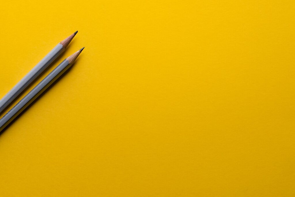 two gray pencils on yellow surface